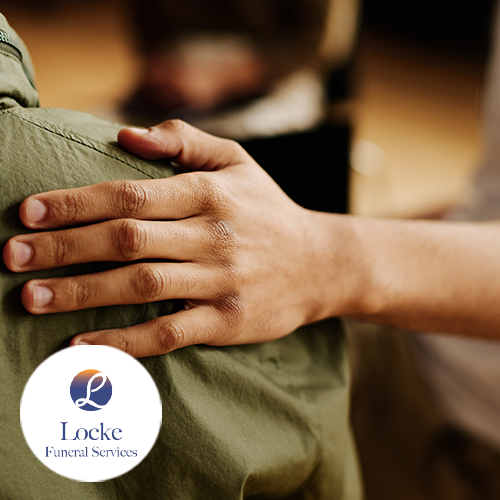 Person's hand on another person's shoulder in comfort.